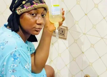 Nigerian woman makes dinner for her husband while receiving drip